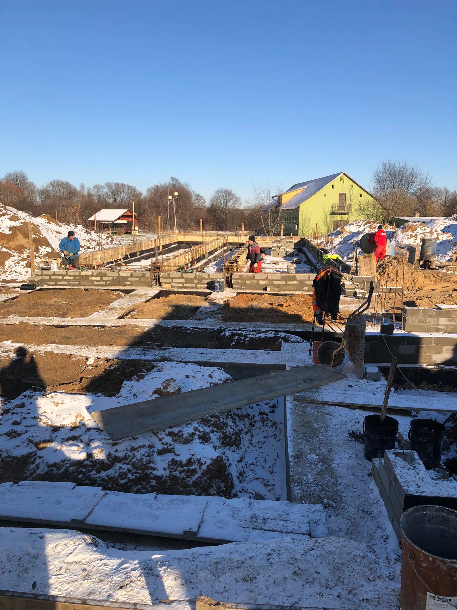 264838258_1137305136808628_7554547732012718759_n Plac budowy pokryty lekkim śniegiem. Robotnicy wykonują prace przy fundamentach.